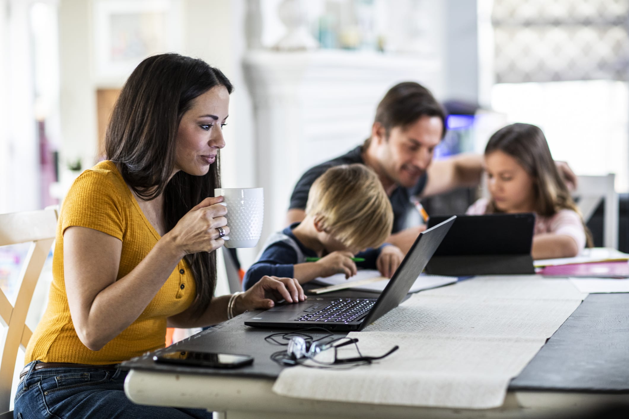 Working mother at dining room table with children