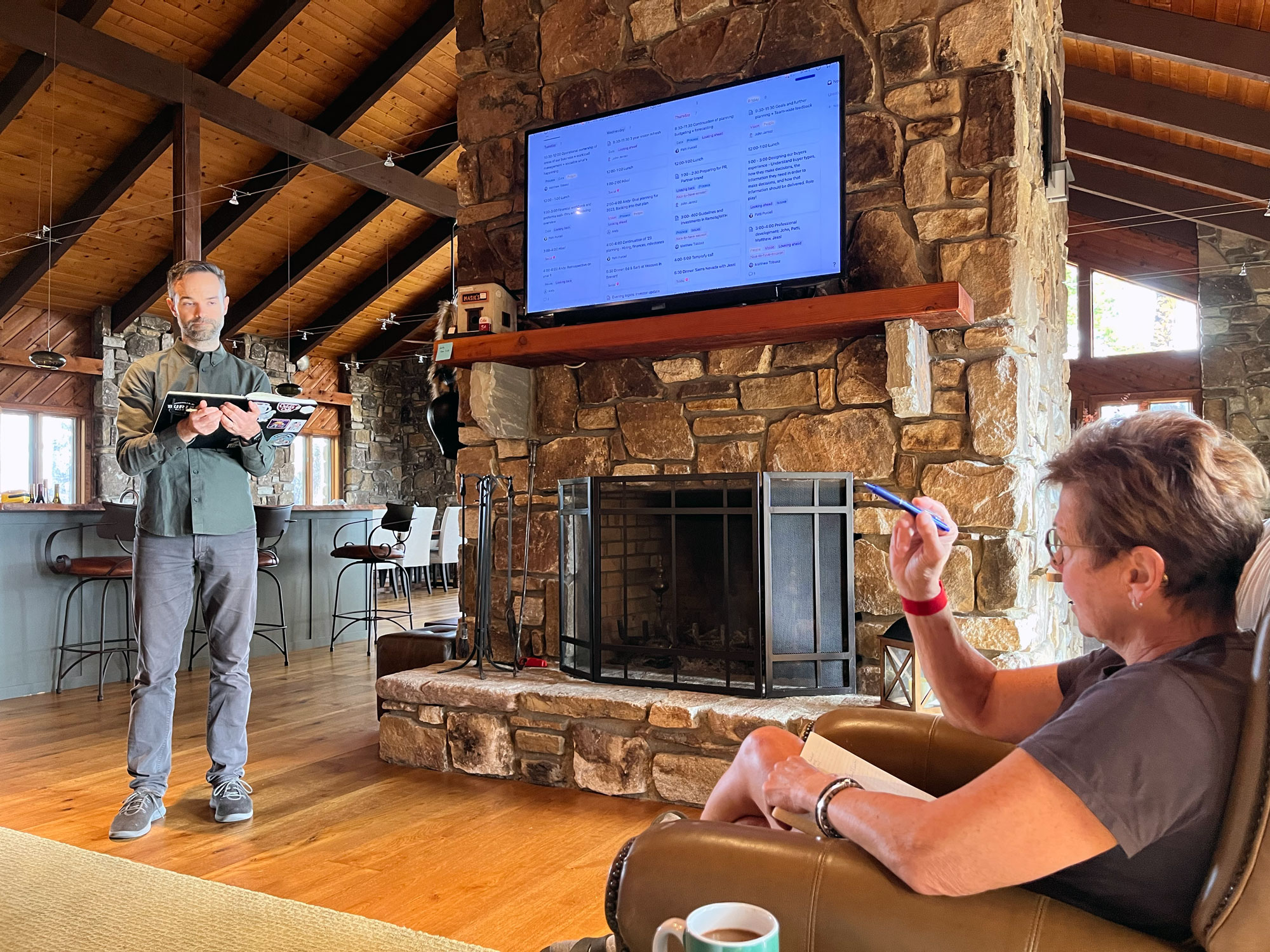 Matthew Tobiasz making a presentation to Patti Purcell in front of fireplace at Sightglass team offsite retreat.