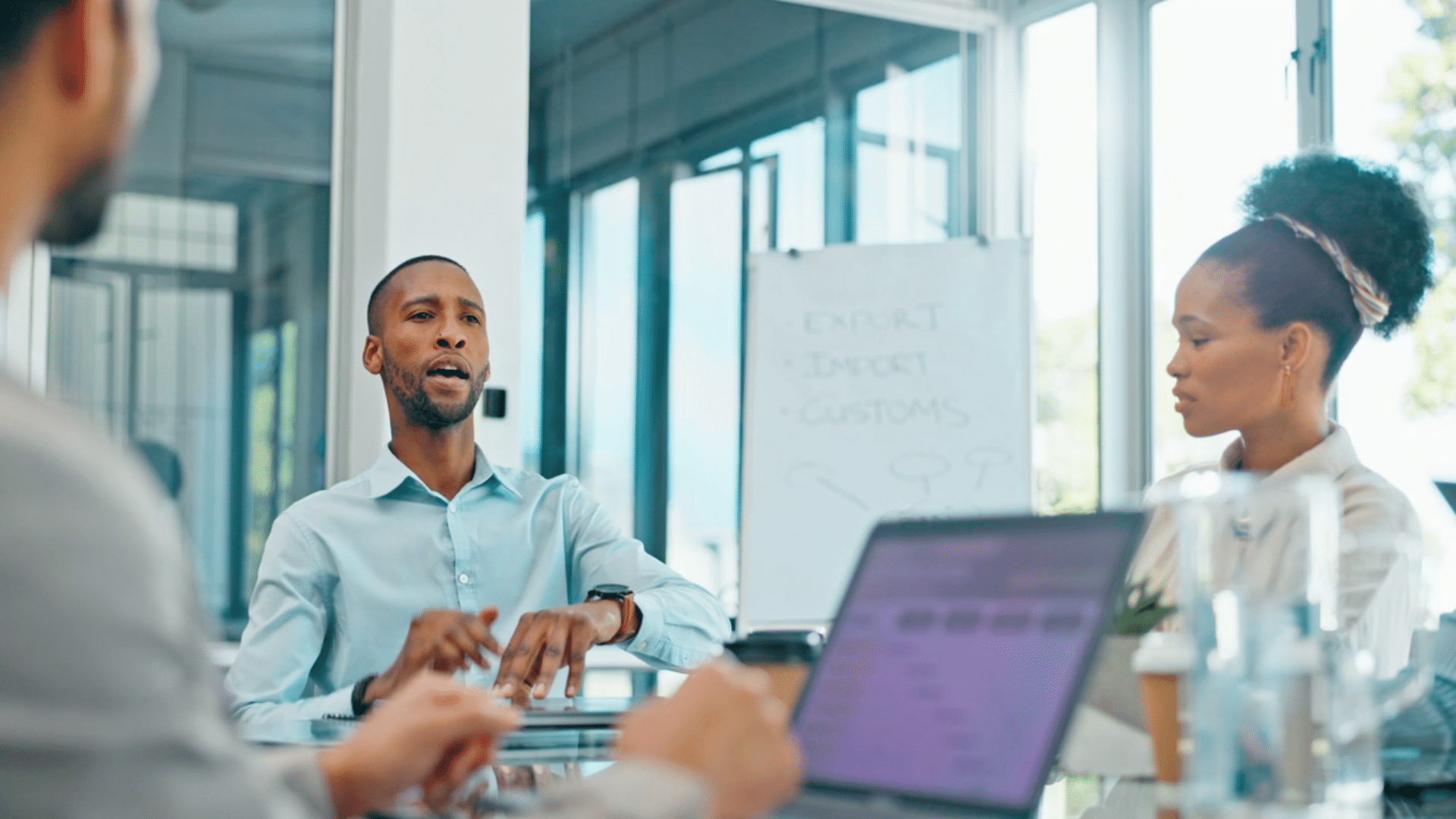 technology entrepreneur sitting at a desk surrounded by team working on a collaborative project.